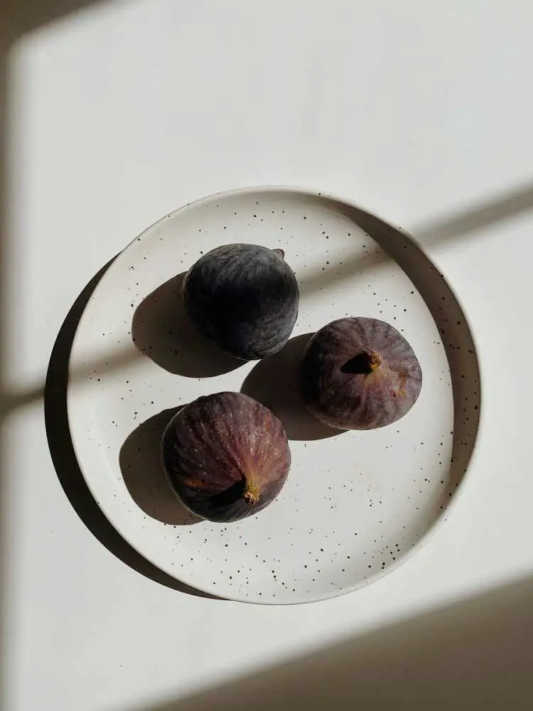 Top view of ripe unpeeled fig fruits placed on white ceramic bowl
